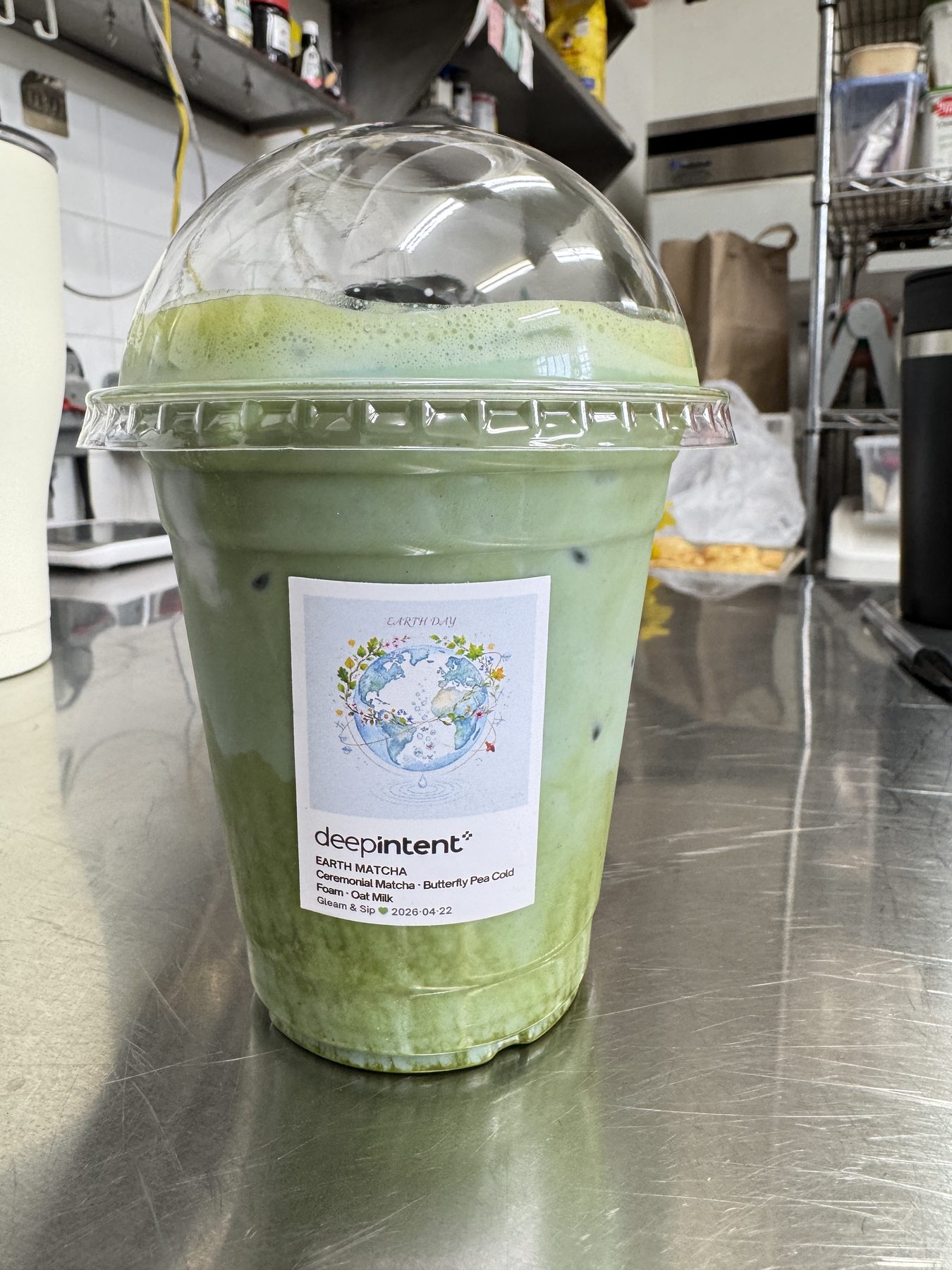 An iced ceremonial matcha co-branded with the DeepIntent logo, made by Gleam & Sip for an Earth Day office activation