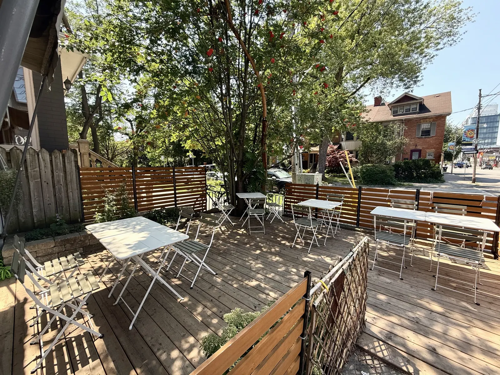 Tree-shaded Gleam & Sip patio looking toward Dupont Street